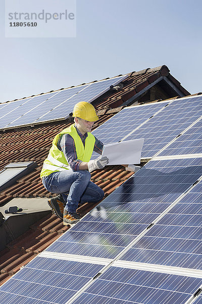 Ingenieur auf dem Dach  der die Sonnenkollektoren kontrolliert