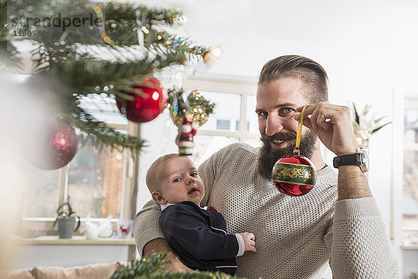 Porträt eines Vaters  der einen kleinen Jungen und eine Weihnachtskugel hält