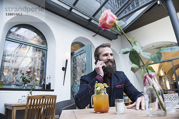 Junger Mann  der ein Mobiltelefon benutzt  während er im Restaurant sitzt