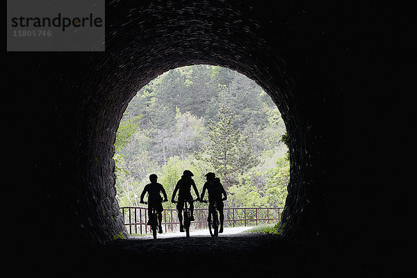 Silhouettierte Radfahrer bei der Einfahrt in den Tunnel