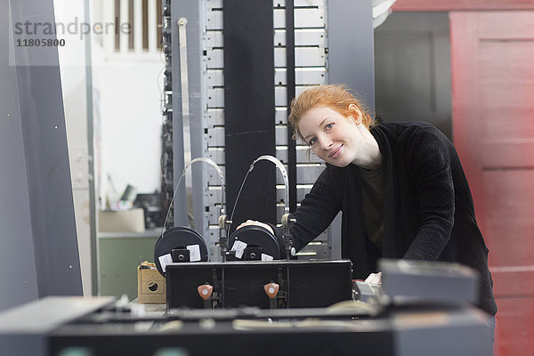 Lächelnde Frau an einer Druckmaschine
