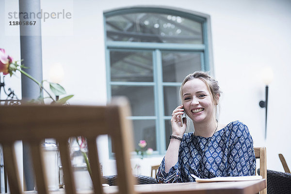 Junge Frau lächelt bei der Benutzung eines Mobiltelefons