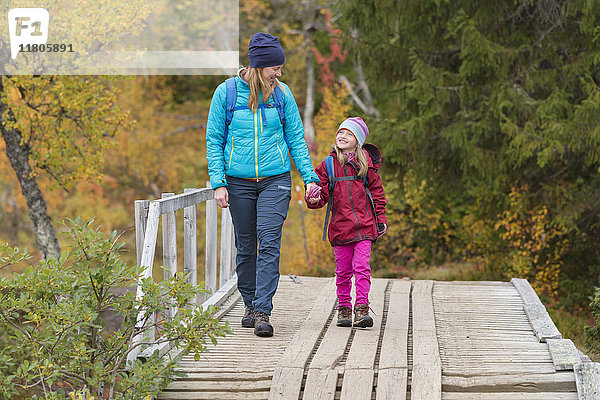Mutter mit Tochter geht über eine Brücke