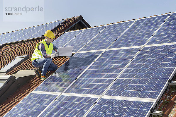 Ingenieur auf dem Dach  der die Sonnenkollektoren kontrolliert