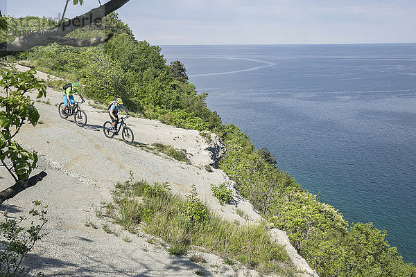 Radfahrer fahren auf felsiger Klippe am Meer