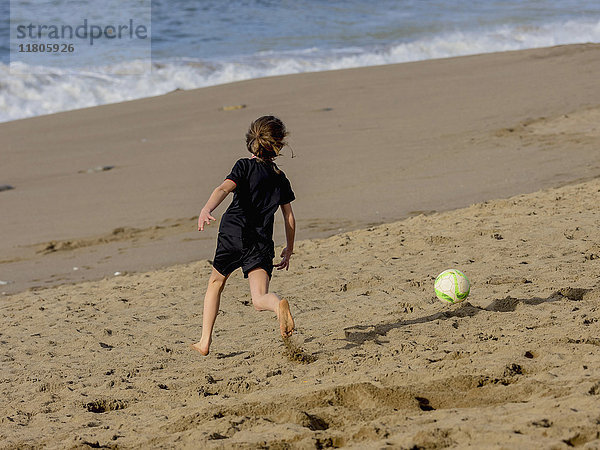 Fußballspielendes Mädchen am Ufer des Strandes