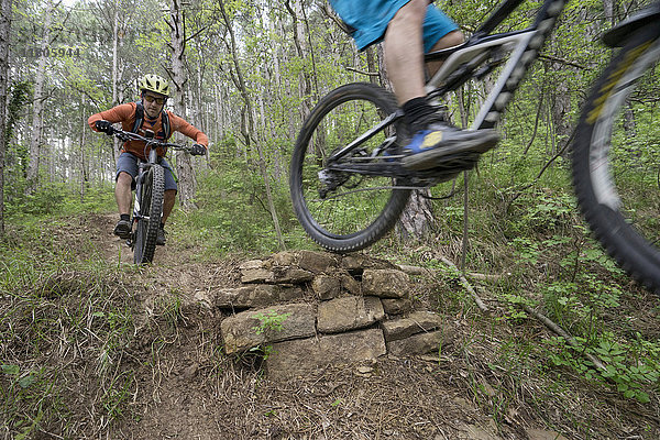 Mountainbiker vollführen Stunt im Wald