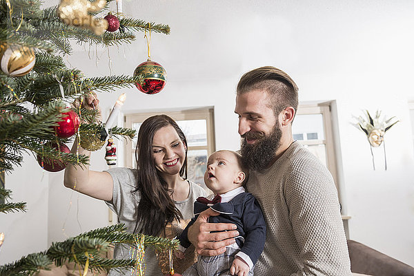 Eltern mit einem kleinen Jungen betrachten den Weihnachtsbaum