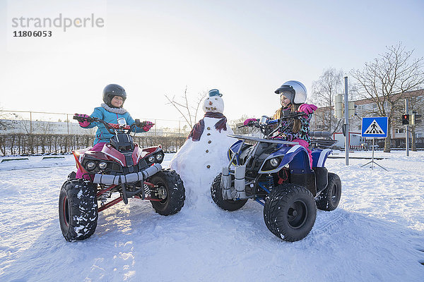 Mädchen fahren Quad auf einem Schneefeld