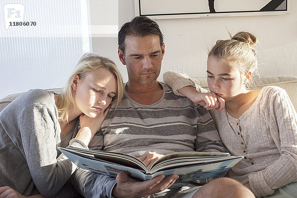 Teenager-Mädchen mit Vater  der ein Buch betrachtet