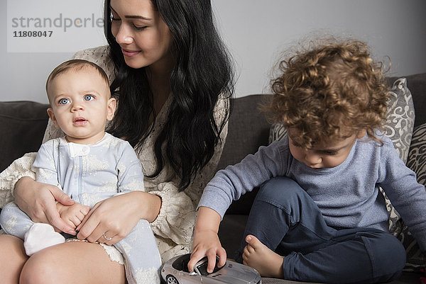 Kaukasische Mutter sitzt mit Söhnen auf dem Sofa