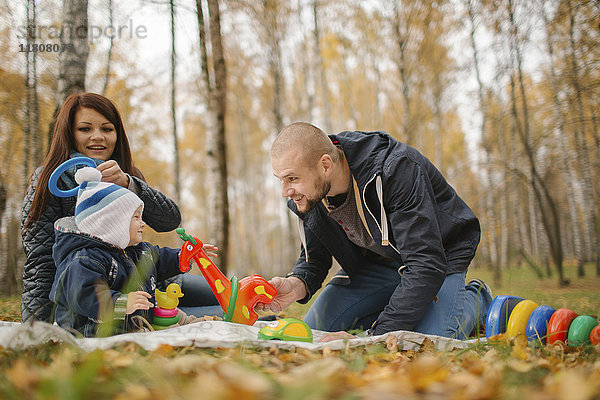 Paar aus dem Nahen Osten spielt im Herbst mit seinem kleinen Sohn im Park