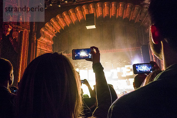 Menschen fotografieren mit Handys bei einem Konzert im Theater