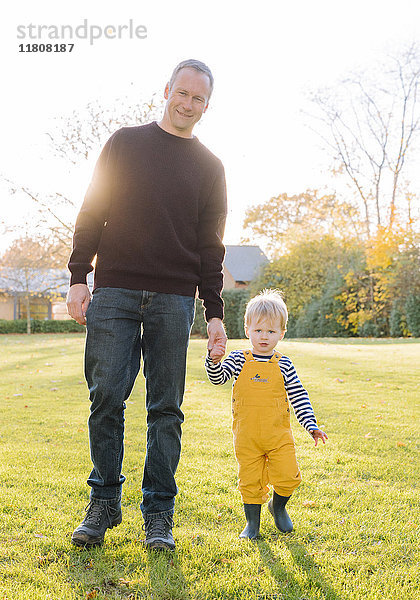 Kaukasischer Vater und Sohn gehen auf einem Feld spazieren