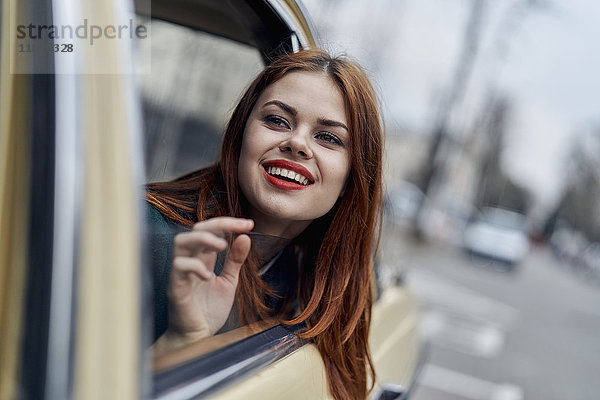 Lächelnde kaukasische Frau auf dem Rücksitz eines Autos