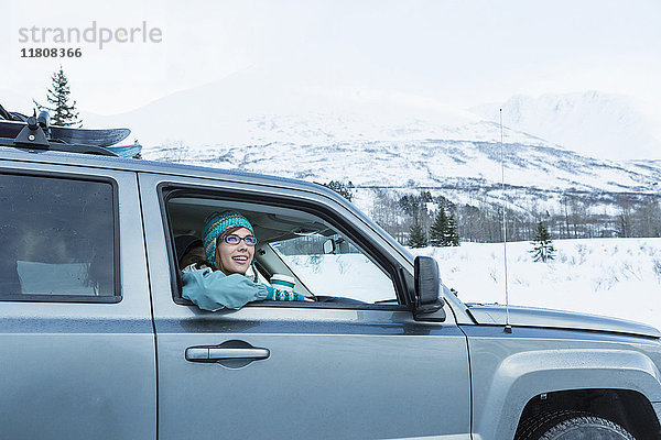 Kaukasische Frau lehnt sich im Winter ins Autofenster