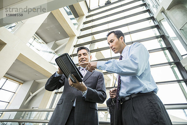 Geschäftsleute benutzen ein digitales Tablet in der Lobby