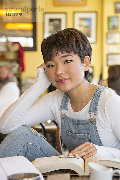 Asiatisches Teenager-Mädchen  das in einem Café ein Buch liest