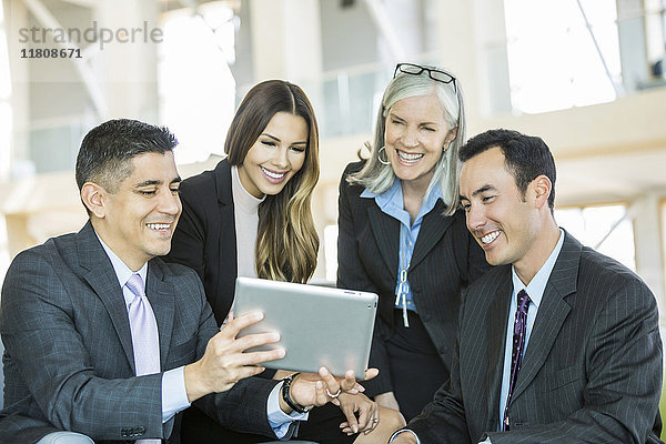 Lächelnde Geschäftsleute  die in der Lobby eine digitale Tafel lesen