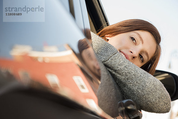 Kaukasische Frau lehnt sich aus dem Autofenster