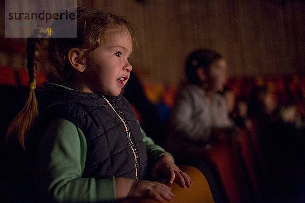 Mädchen lehnt auf einem Stuhl und schaut einen Film im Kino