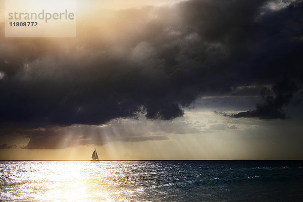 Sonnenstrahlen durch Gewitterwolken über Segelboot