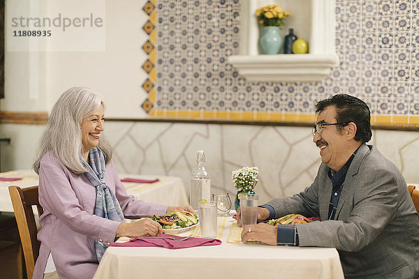 Lächelndes älteres Paar isst Salat und lacht im Restaurant