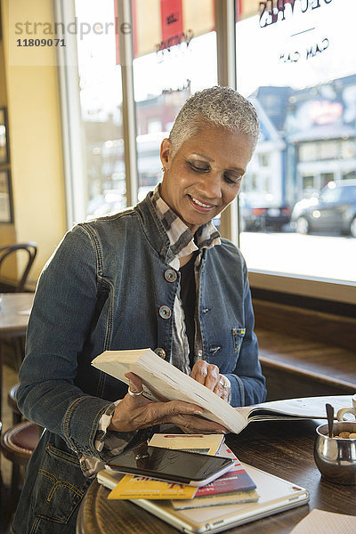 Gemischtrassige Frau liest Reiseführer in einem Café