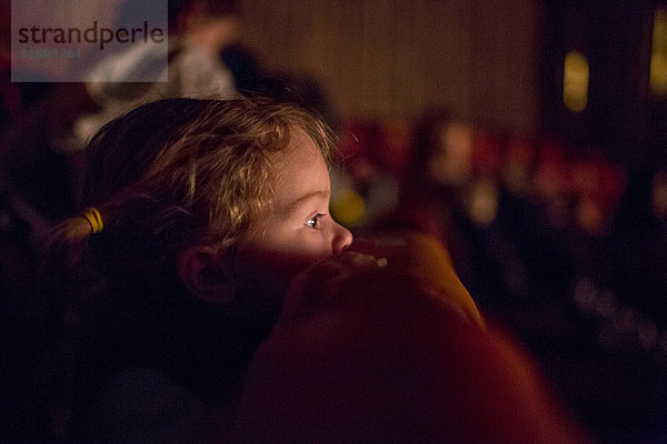 Kaukasisches Mädchen lehnt auf einem Stuhl und schaut einen Film im Kino