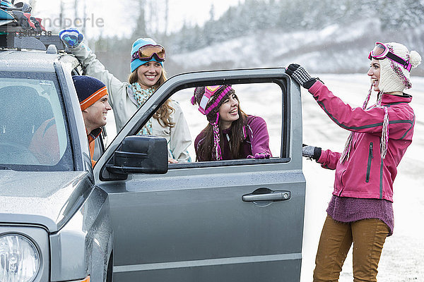 Lachende Freunde beim Auto im Winter