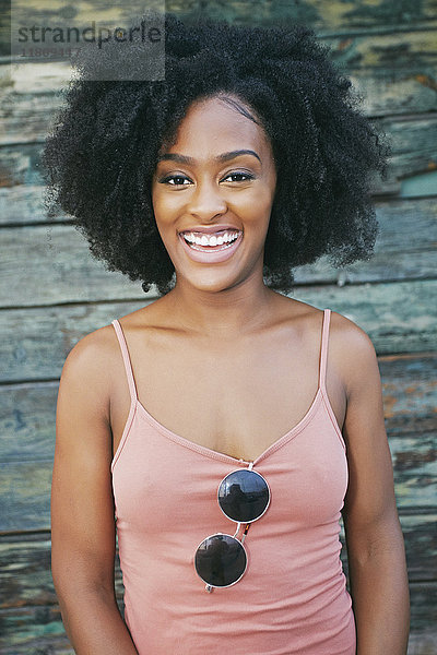 Lachende schwarze Frau in der Nähe einer Holzwand