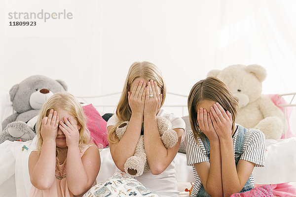 Schwestern aus dem Nahen Osten sitzen im Schlafzimmer auf dem Boden und bedecken die Augen