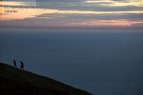 Wanderer besteigen den Berg bei Sonnenuntergang