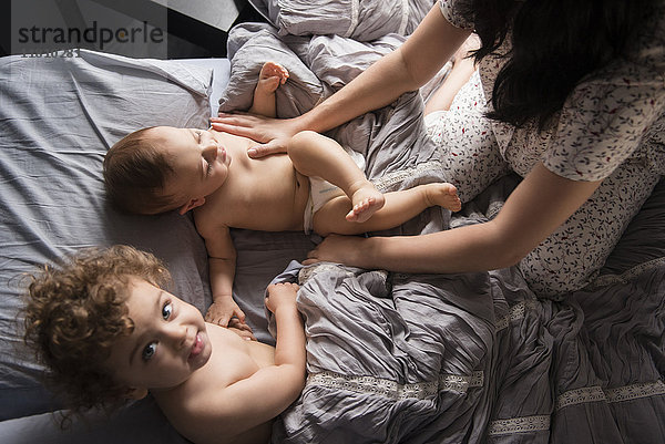 Kaukasische Mutter spielt mit Söhnen im Bett