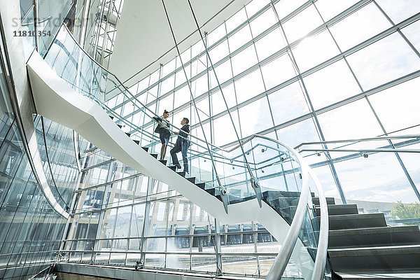 Entfernte gemischtrassige Geschäftsleute  die auf einer Treppe stehen und sich unterhalten