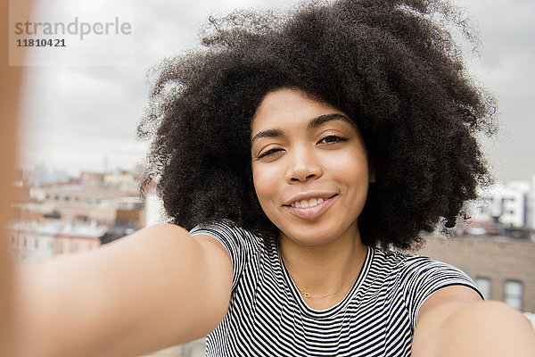 Lächelnde afroamerikanische Frau posiert für ein Selfie auf dem Dach