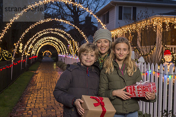 Kaukasische Familie mit Weihnachtsgeschenken auf dem Bürgersteig