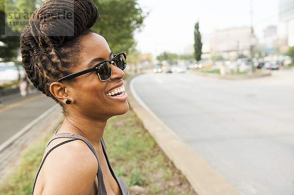 Afroamerikanische Frau mit Zöpfen lachend in der Nähe der Straße