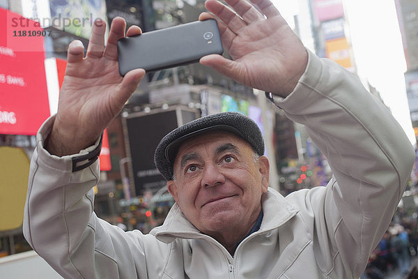 Hispanischer Mann posiert für Handy-Selfie in der Stadt