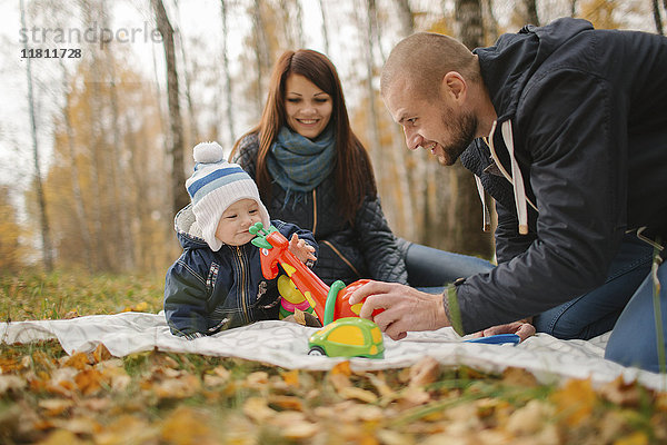 Paar aus dem Nahen Osten spielt im Herbst mit seinem kleinen Sohn im Park