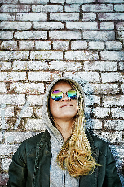 Kaukasische Frau mit Sonnenbrille in der Nähe einer Mauer