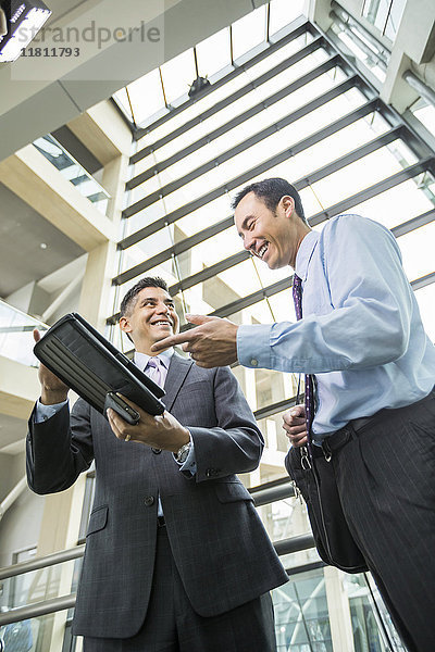 Lächelnde Geschäftsleute mit digitalem Tablet in der Lobby