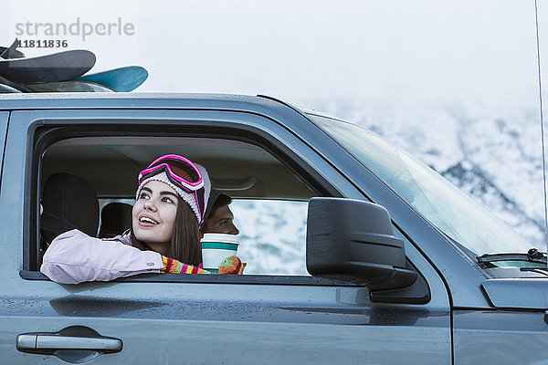 Gemischtrassige Frau lehnt sich im Winter an ein Autofenster