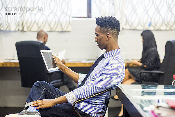 Schwarzer Mann benutzt digitales Tablet im Büro