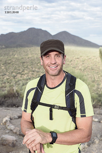 Porträt eines lächelnden hispanischen Mannes beim Wandern in der Wüste