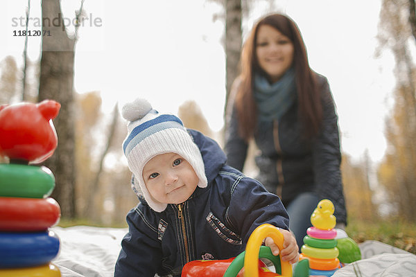 Mutter aus dem Nahen Osten beobachtet ihren kleinen Sohn beim Spielen mit Spielzeug im Park