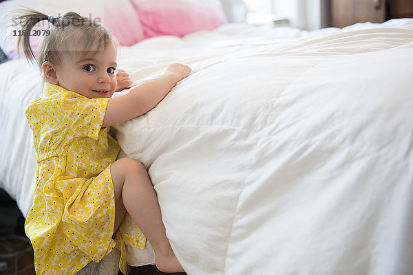 Kaukasisches Babymädchen klettert auf Bett