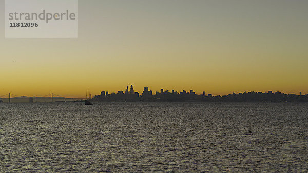 Silhouette der städtischen Skyline am Wasser bei Sonnenuntergang