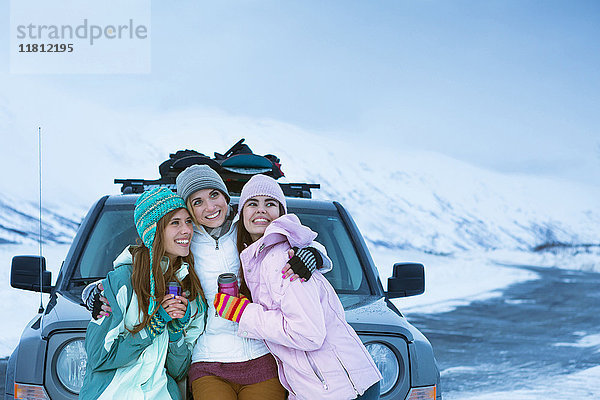 Frauen  die sich im Winter in der Nähe des Autos umarmen