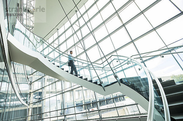 Gemischtrassiger Geschäftsmann  der eine Treppe hinabsteigt